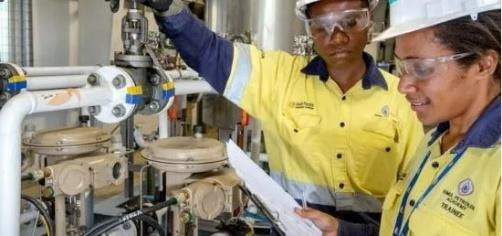 Site personnel in high-visibility gear reviewing paperwork at a processing plant